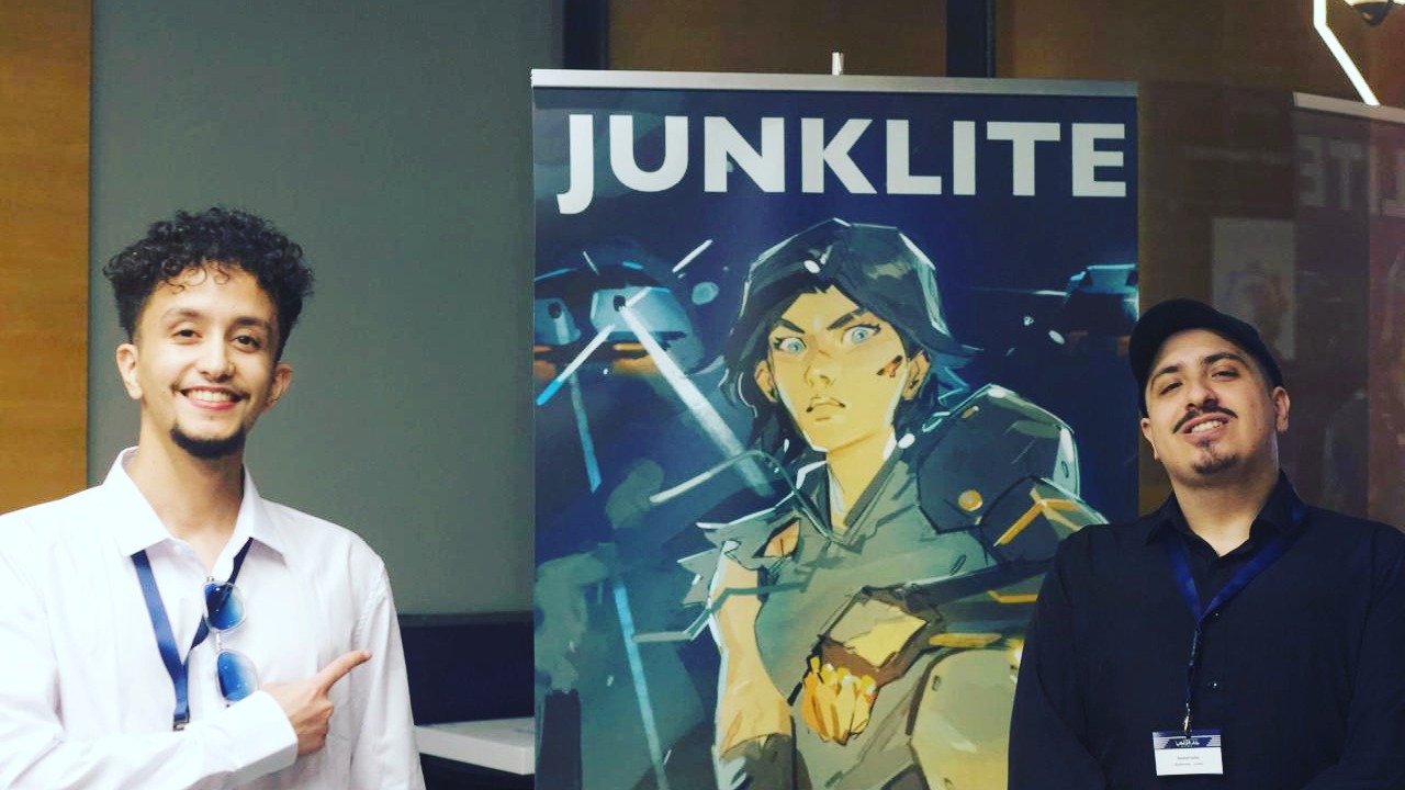 Two members of the Golden Game Company team beside a Junklite poster